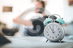 Alarm clock in the morning. Young wakes up and stretches in the blurry background