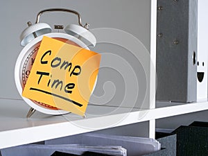 Alarm clock on an office shelf and compensation Comp time inscription.