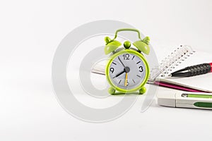 Alarm clock, open notebook, usb stick and pencil on white background