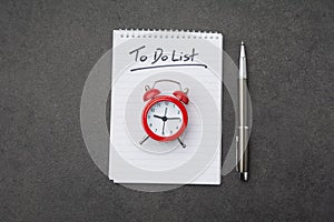 Alarm clock over spiral note pad with the to do list as a time management concept