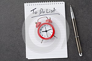 Alarm clock over spiral note pad with the to do list as a time management concept