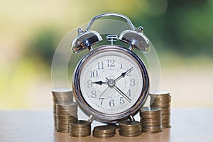 Alarm clock and a pile of golden coins on the table, Concept of