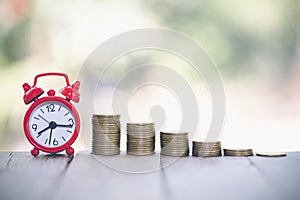 Alarm clock and a pile of golden coins on the table, Concept of opportunity cost time and Money saving