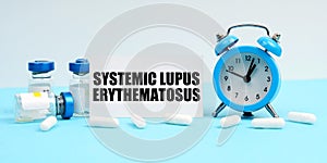 An alarm clock, pills, injections and a card with the inscription - Systemic Lupus Erythematosus