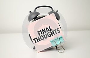alarm clock with pink sticker with the text final thoughts