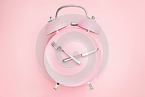 Alarm clock and plate with cutlery . Concept of intermittent fasting, lunchtime, diet