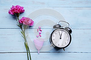 Alarm clock with roses, pills and sanitary cup