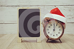 alarm clock with santa hat on wooen background time for christmas