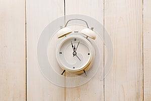 Alarm clock showing almost 12 o clock, on old white wooden floor background
