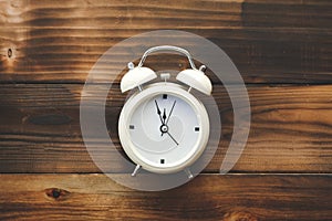 Alarm clock showing almost 12 o clock, on old wooden floor background