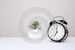 An alarm clock showing 7 o'clock standing on a white table with copy space, everyday shedule and morning wake up concept