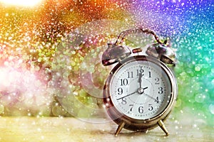 Alarm clock showing midnight on New Year or Christmas day with colorful abstract bokeh