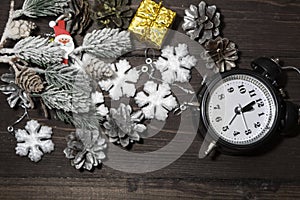 An alarm clock, snowflakes, a snow-covered spruce branch and silvery cones