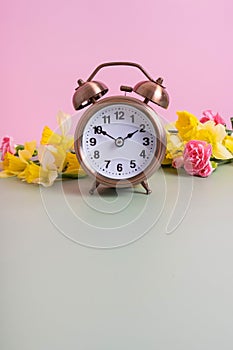 Alarm clock with spring flowers and copy space. Spring time, daylight savings concept, spring forward