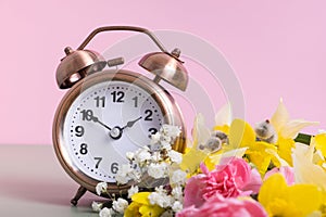 Alarm clock with spring flowers. Spring time, daylight savings concept, spring forward