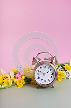 Alarm clock with spring flowers. Spring time, daylight savings concept, spring forward