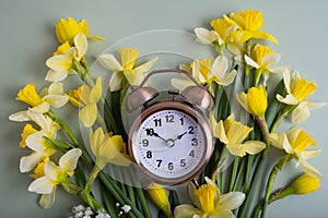 Alarm clock with spring flowers top view. Spring time, daylight savings concept, spring forward