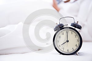 alarm clock standing on bedside table going to ring early morning
