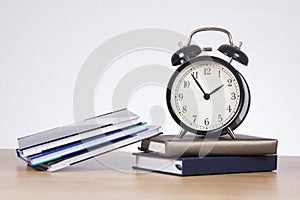 Alarm clock standing on pile of books