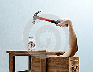 The alarm clock stands on the bedside table, a hand with a hammer photo