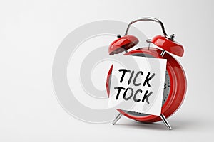 Alarm clock and sticky note with words TICK TOCK photo