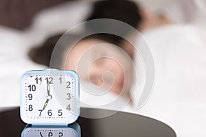 Alarm clock on table in front of sleeping young couple