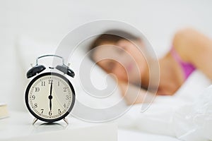 Alarm clock on table and woman in background photo