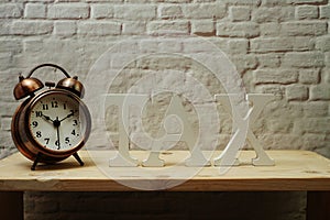 Alarm clock and Tax alphabet letter on wooden background