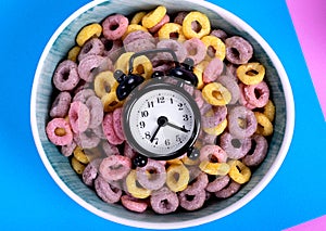 Alarm clock on top of multicolored breakfast cereals