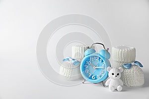 Alarm clock, toy bear and baby booties on white background, space for text. Time to give birth