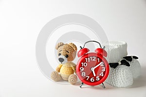 Alarm clock, toy bear and baby booties on white background, space for text. Time to give birth