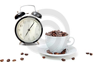 The alarm clock and white cup filled by coffee beans