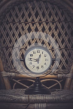 Alarm clock on wicker chair.