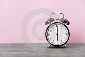 Alarm clock on wood table with pink background and copy space