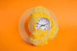 Alarm clock in yellow hat on the orange background