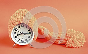 Alarm clock in yellow hat on the orange background
