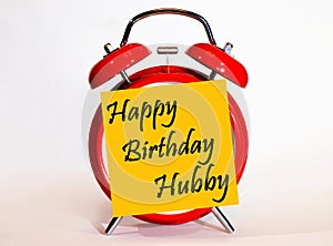 An alarm clock and a yellow note with text happy Birthday hubby.