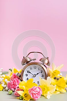 Alarm clock with yellow and pink flowers. Spring time, daylight savings concept, spring forward