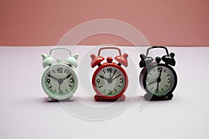 Alarm clocks with different time composition on pink  background