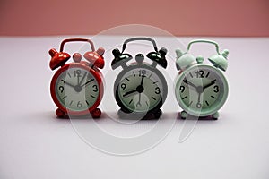 Alarm clocks with different time composition on pink  background