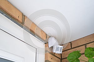 Alarm PIR sensor located by the front door of a house, inside a porch.