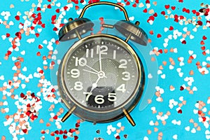 Alarm showing 7 o`clock with colorful heart confetti, holidays time concept