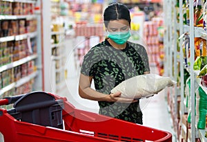 Alarmed female wears medical mask against coronavirus while grocery shopping in supermarket or store- health, safety and