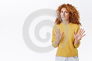 Alarmed and worried curly redhead woman calm down person, saying dont shoot, raising arms, begging to stop, look freak photo