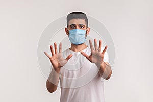 Alarming scared panicking man in hygienic mask gesturing stop, afraid of coronavirus infection