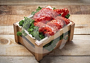 Alaskan King Crab Cooked steam or Boiled seafood on green curly parsley in wooden box with wood background - Fresh red crab