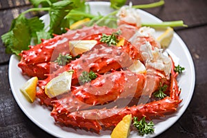 Alaskan King Crab Legs cooked seafood with lemon spices on white plate in the wooden table - red crab hokkaido