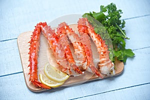 Alaskan King Crab Legs Cooked on wooden cutting board with lemon parsley - red crab hokkaido seafood served table
