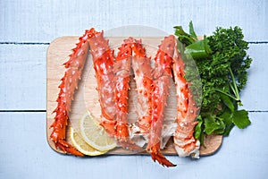 Alaskan King Crab Legs Cooked on wooden cutting board with lemon parsley - red crab hokkaido seafood served table