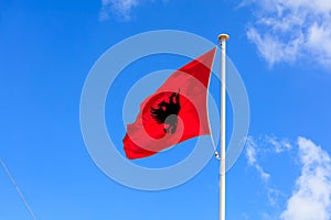 Albania flag. Albanian flag on a pole waving on blue sky background